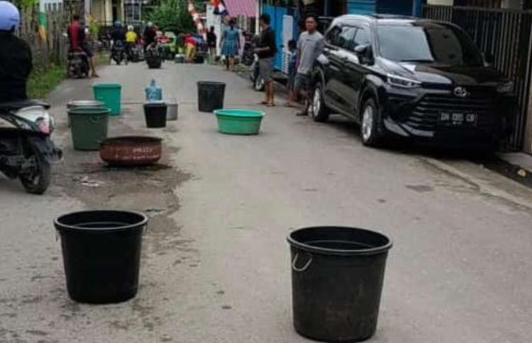 Warga kelurahan bukit mambual, Luwuk Selatan, Kabupaten Banggai, menghamburkan loyang dan ember penampungan air di jalan raya Sabtu (23/7/2022) (Foto: istimewa)
